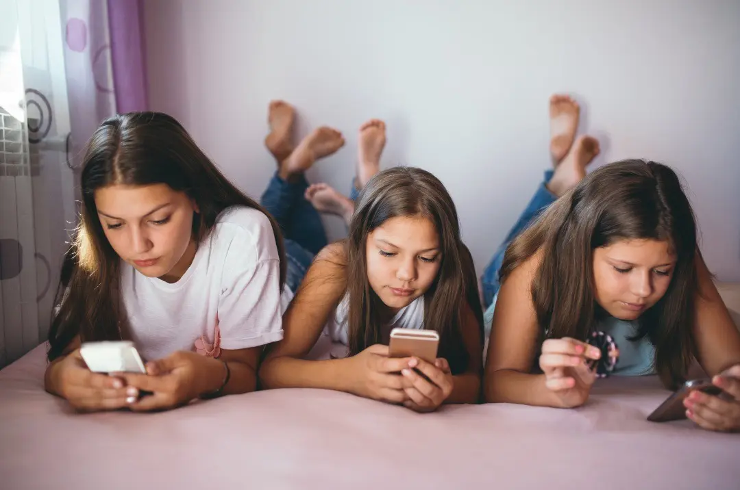 Young people engrossed in their devices, potentially accessing harmful social media trends, highlighting the risks associated with online content consumption such as Tide Pod Challenge, NyQuil Chicken, Benadryl Challenge .