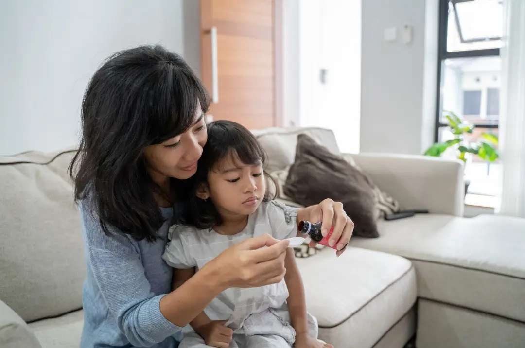 Young woman administering over-the-counter medicine to her child, ensuring the child's well-being and health.