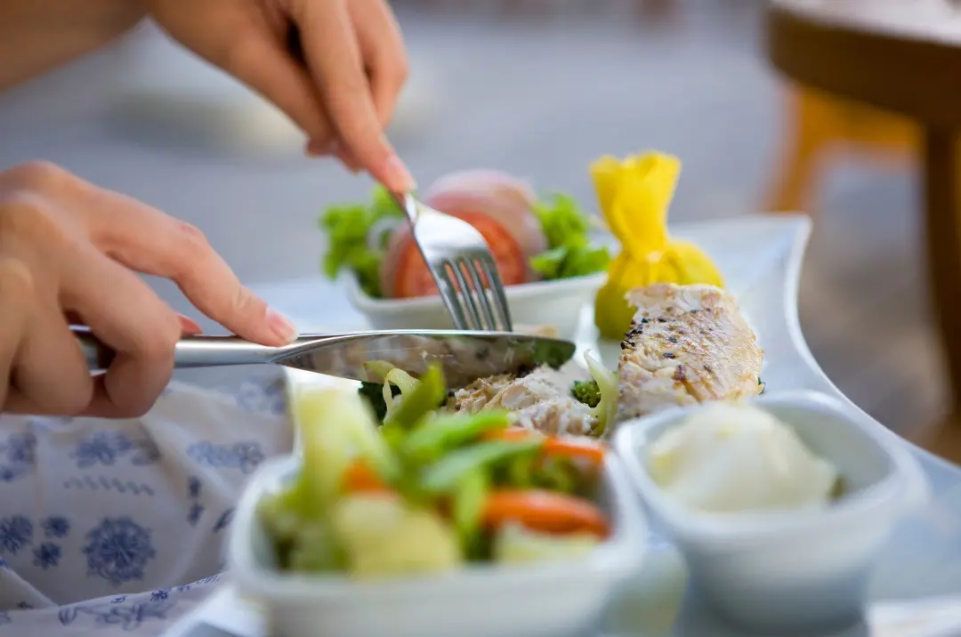 Image of a person enjoying a plate of food, savoring a meal, using tips to avoid food poisoning.