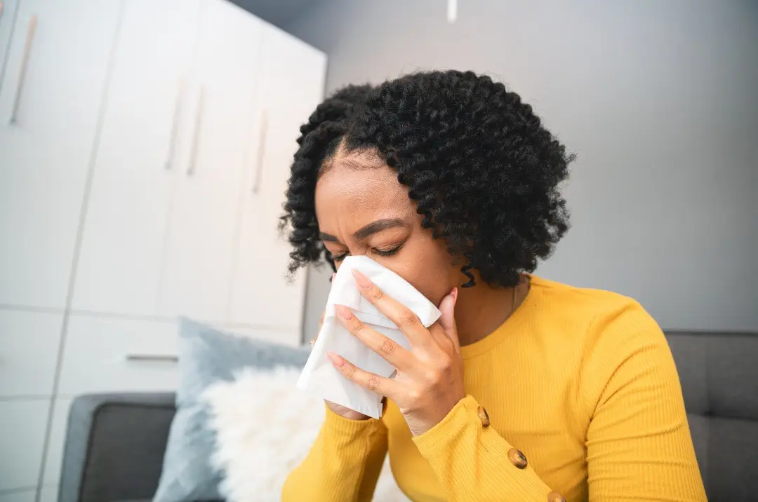 Image of a woman blowing her nose, possibly after exposure to diphenhydramine or benadryl overdose, highlighting the need for respiratory care and relief in such situations.