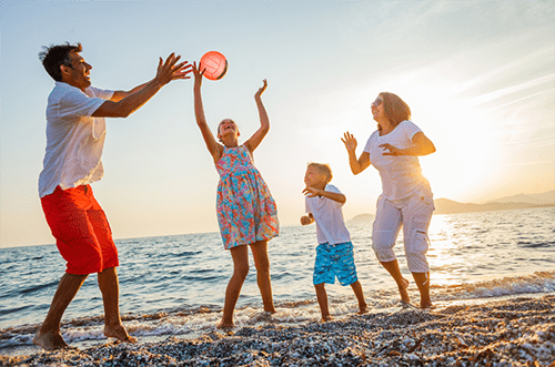 Photo of a family playing on a beach, illustrating sun poisoning safety practices, including the use of sunscreen, protective clothing, and shade, to prevent sunburn and skin damage during outdoor activities.