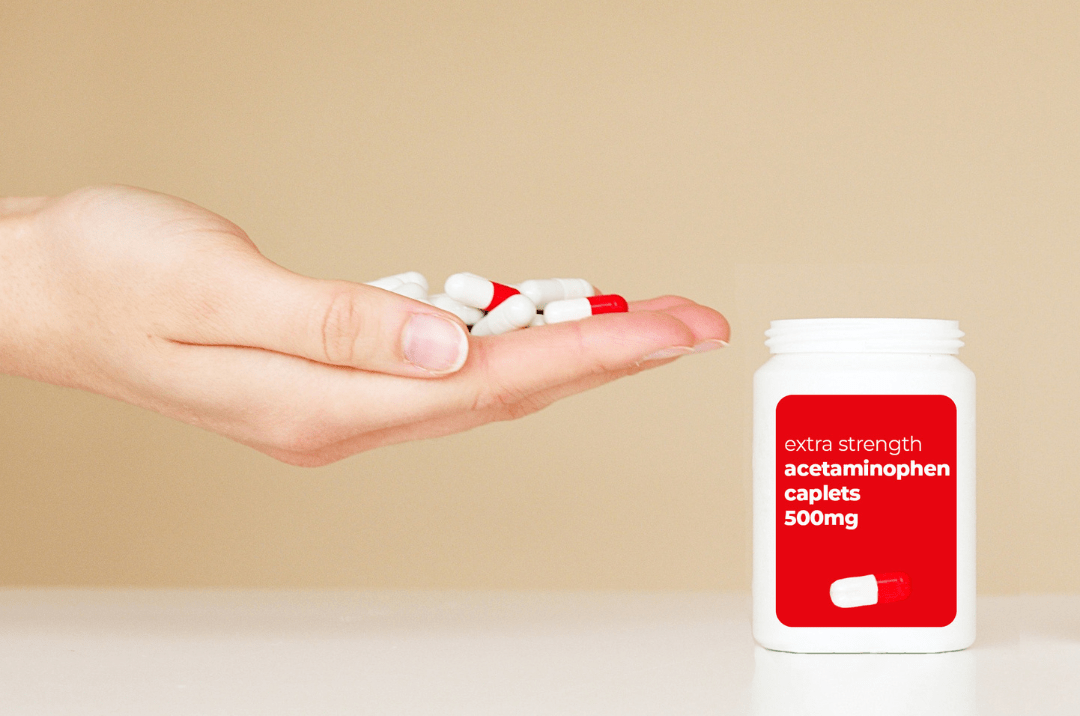 Photo of a woman's hand holding enough red and white pills to create an acetaminophen overdose.